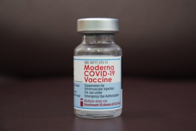 Moderna Covid-19 vakcīnu pudelīte tuvplānā uz tumša fona