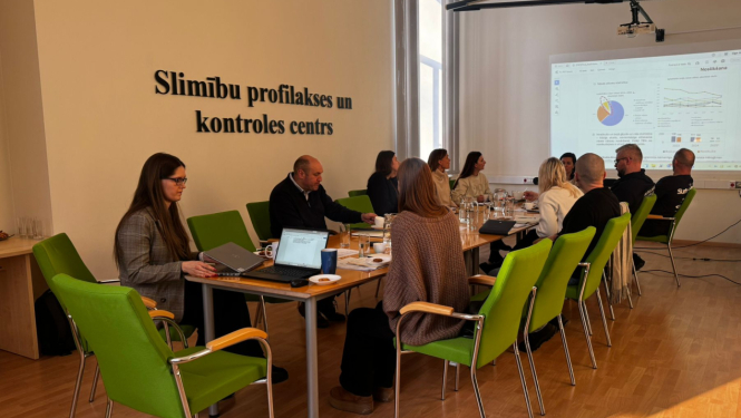 Cilvēki sapulcē sēž pie galda