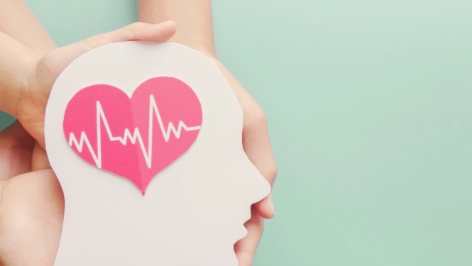 uz gaisī zaļa fona cilvēku rokas tur galvu,kuraiuzzīmēta sirds ar kardeogrammas rakstu