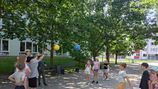 Bērni vasarā uz ielas spēlē bumbu