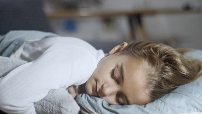 meiteniīte saldi guļ zem segas