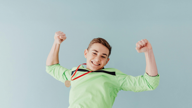 Uz pelēka fona priecīgs pusaudzis zaļā kreklā