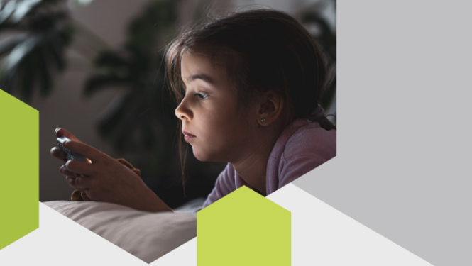 bērns gultā skatās telefona ekrānā