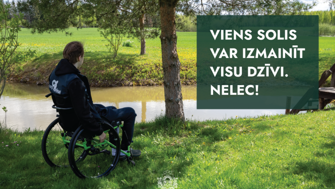 vīrietis ratiņkrēslā sēž upes malā un skatās ūdenī