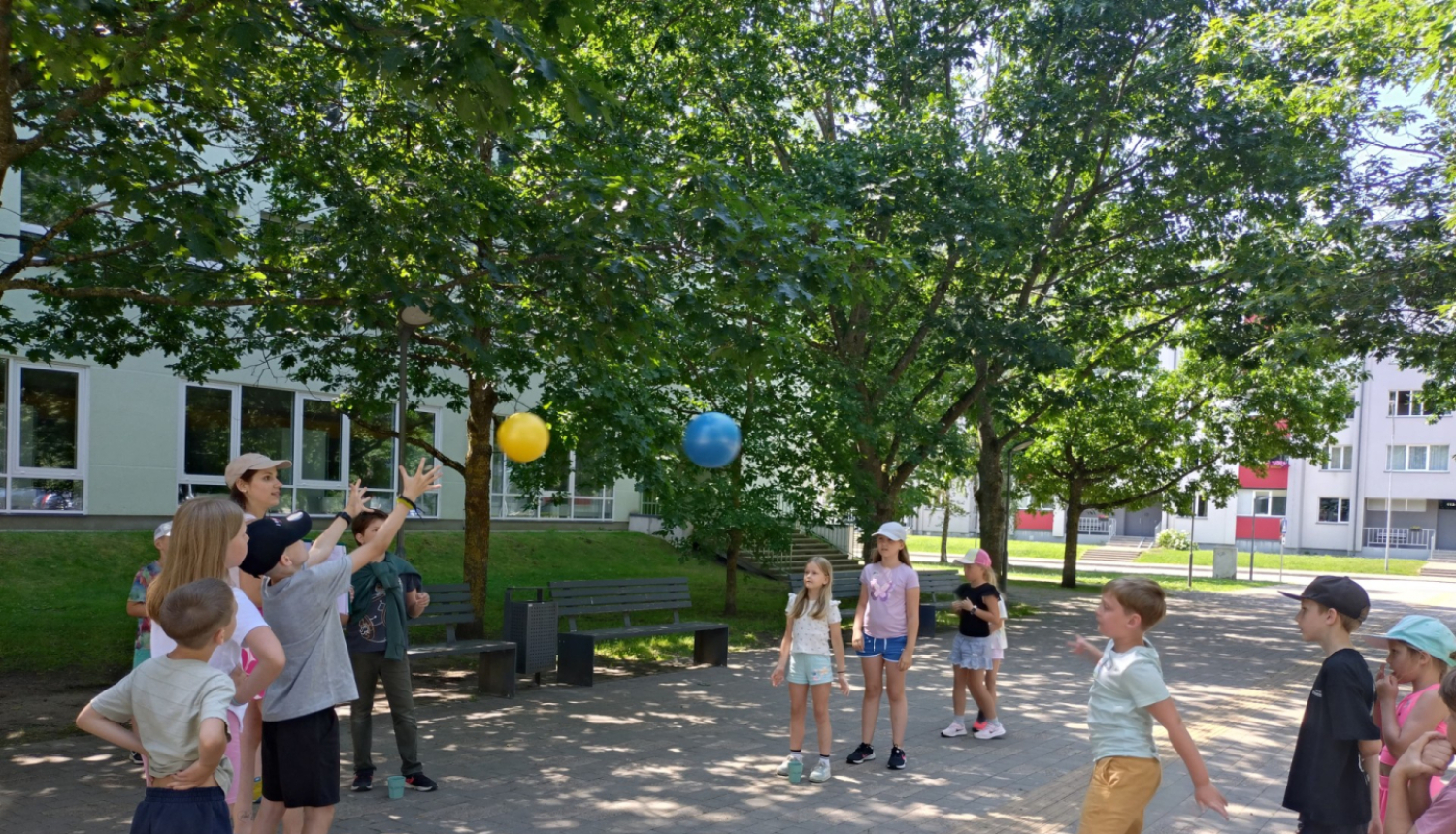Bērni vasarā uz ielas spēlē bumbu
