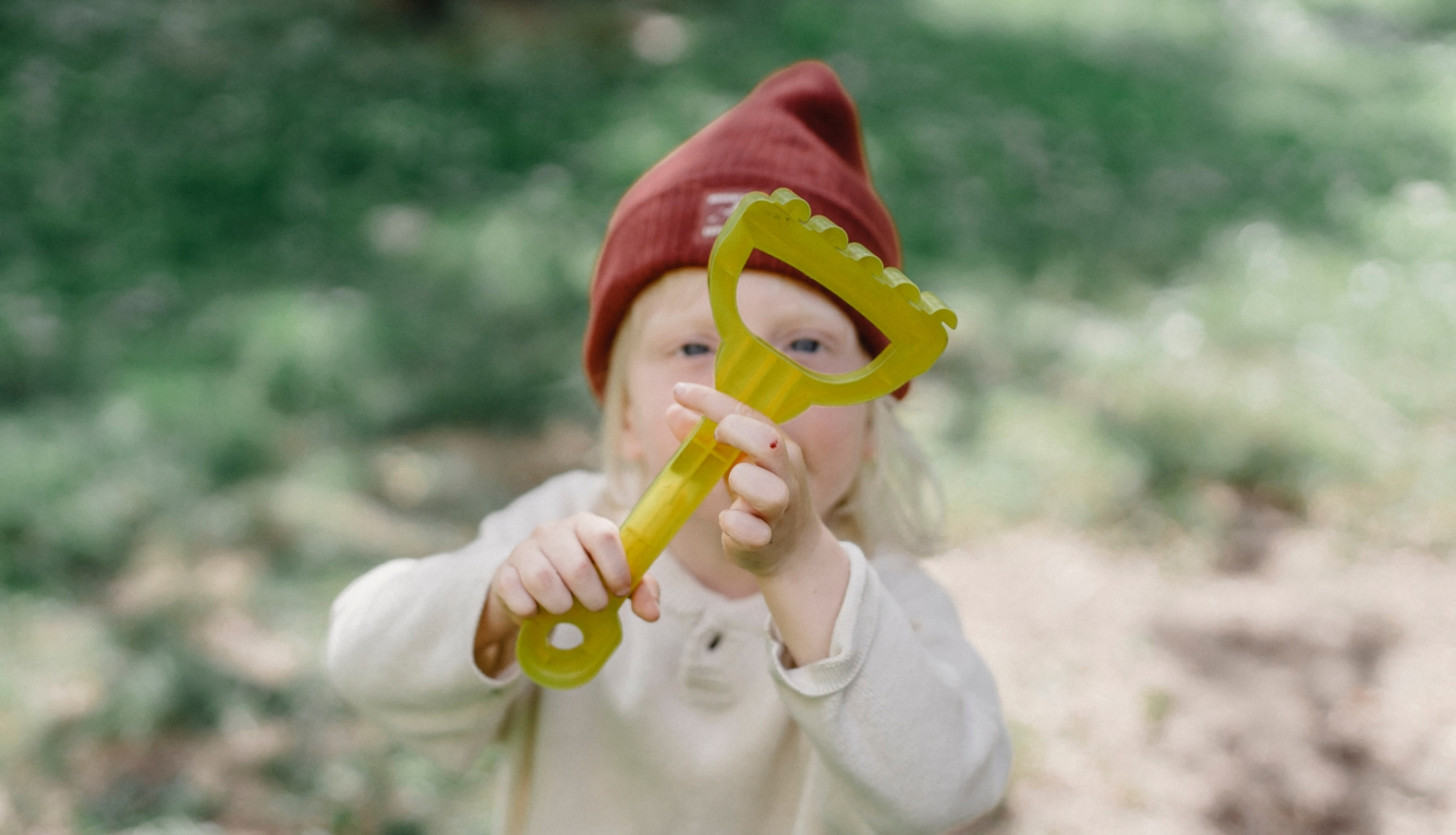Vasarā bērns tur paceltu dārza grābekli
