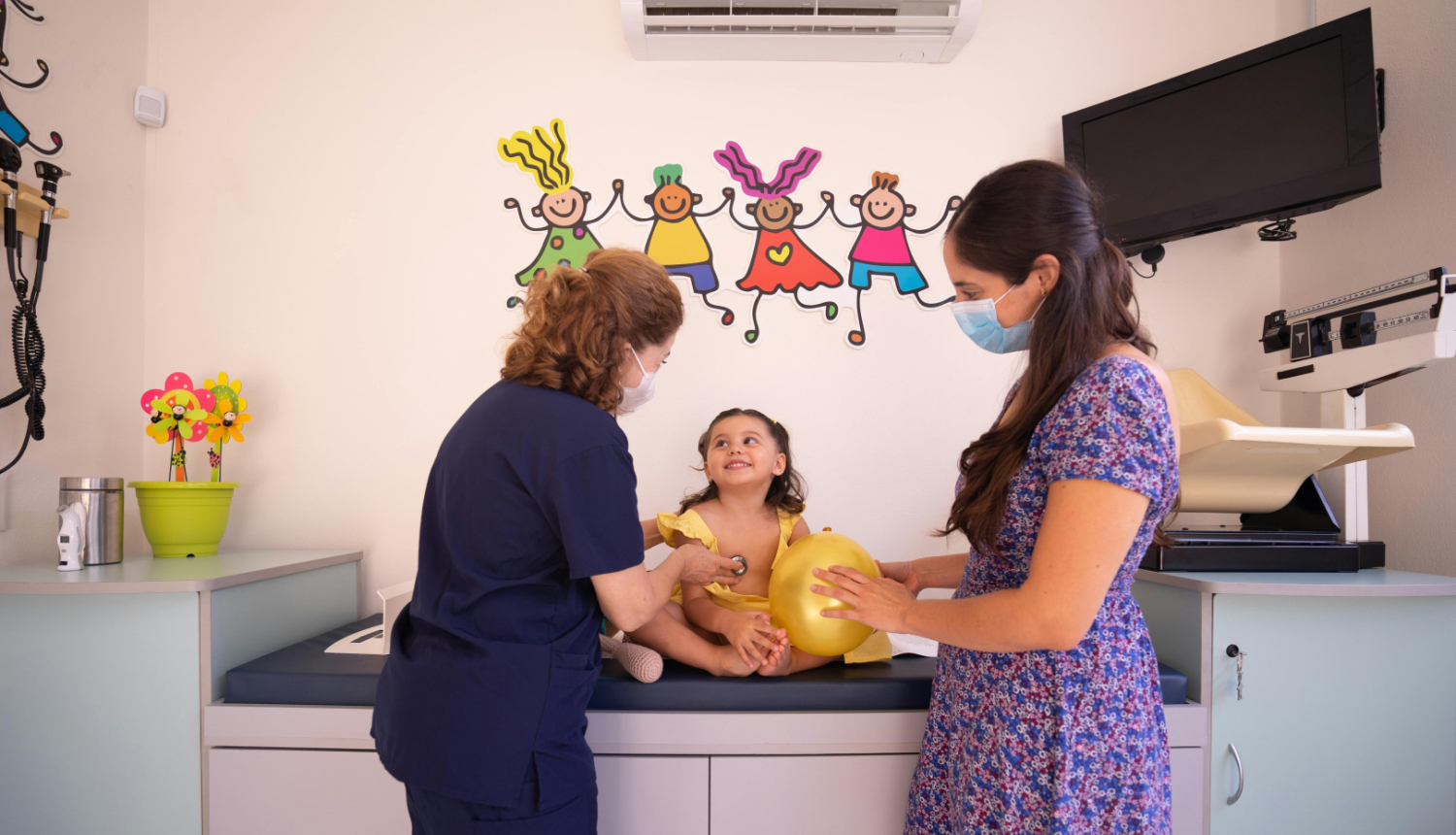 mamma violetā kleitā pie ārsta uz apksti ar mazu meitenīti