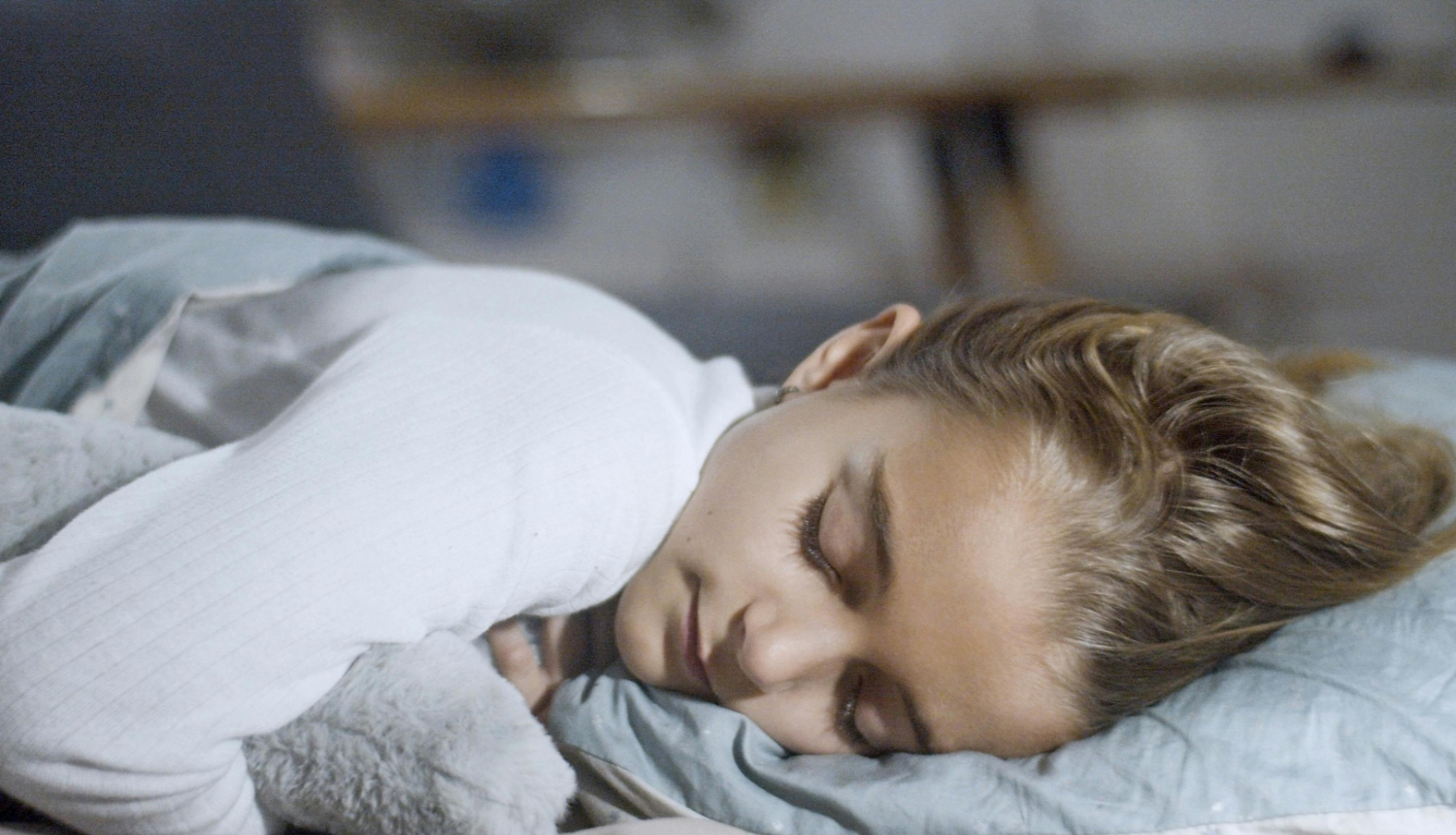 meiteniīte saldi guļ zem segas