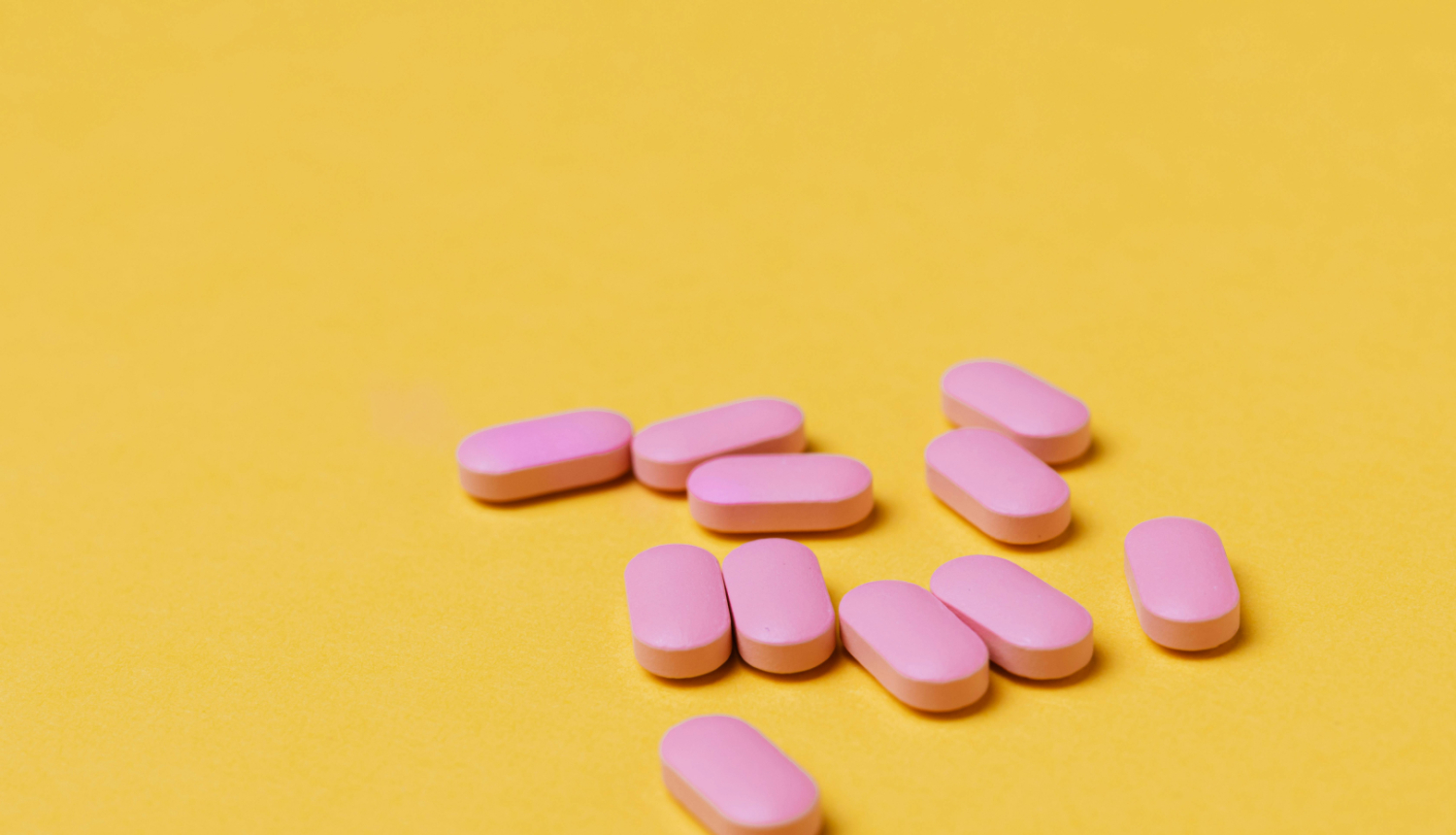 Rozā tabletes uz dzeltena fona