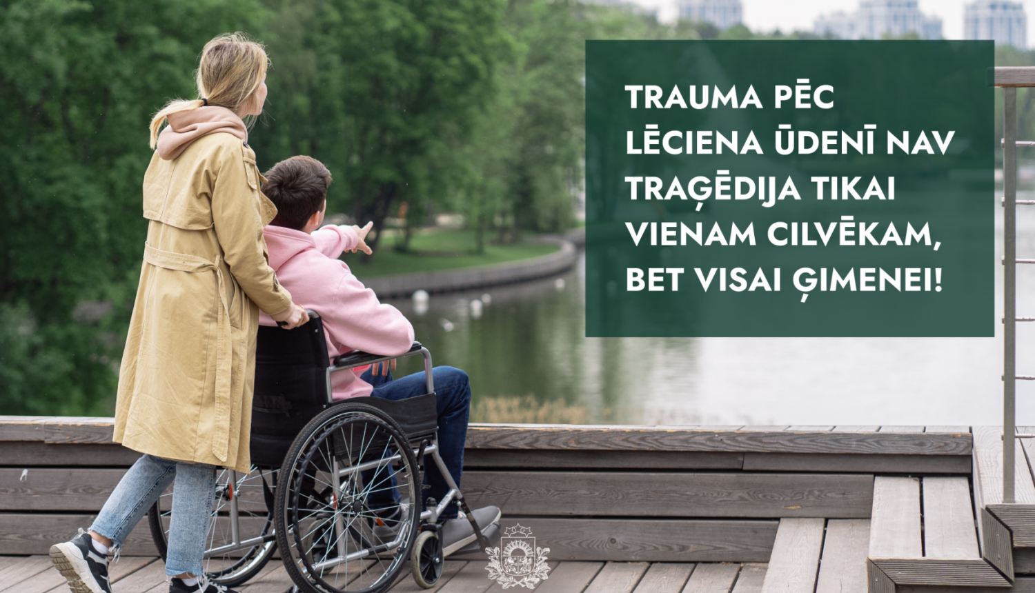 māte ved bērnu ratiņkrēslā pa upes laipu