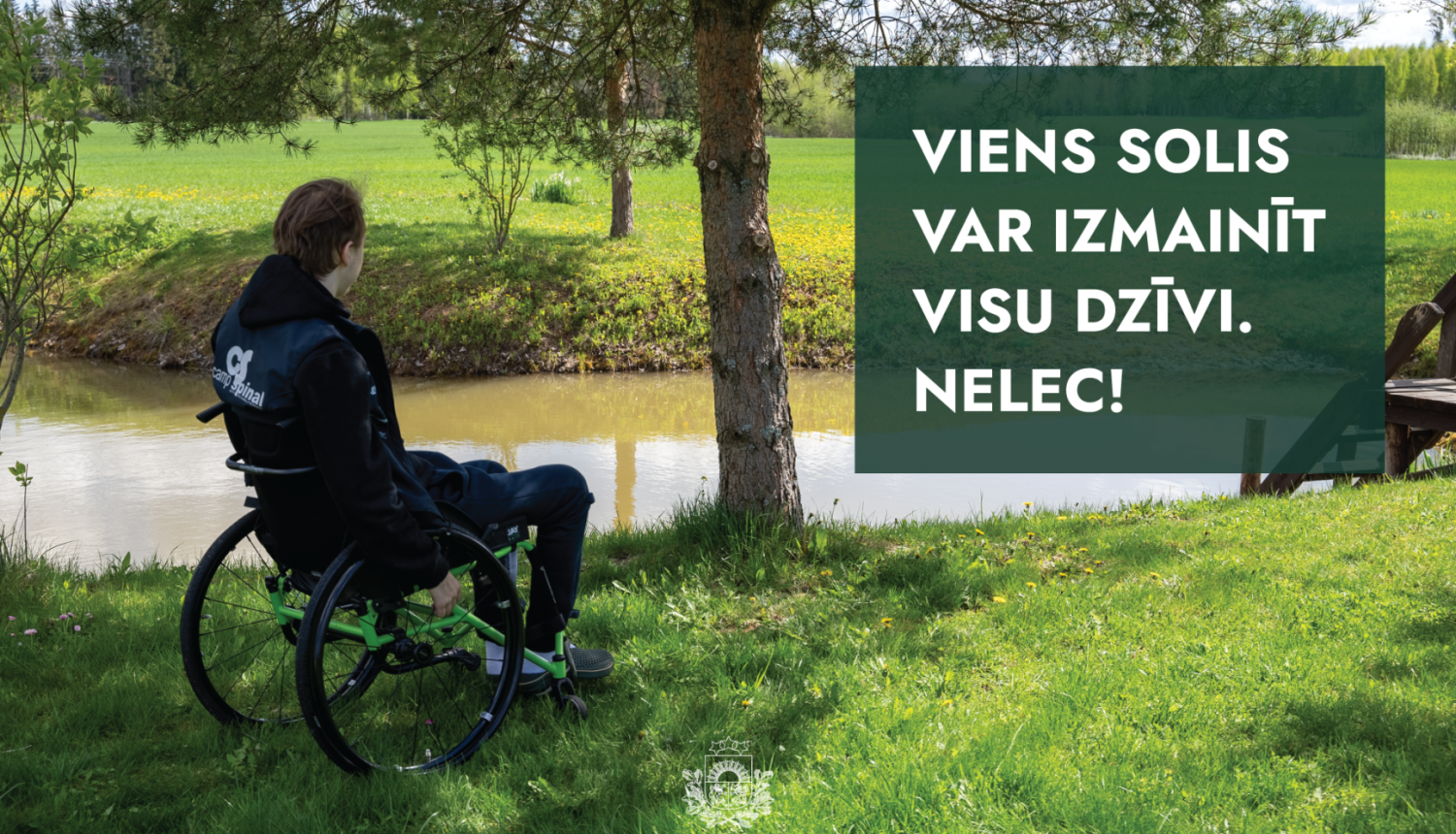 vīrietis ratiņkrēslā sēž upes malā un skatās ūdenī