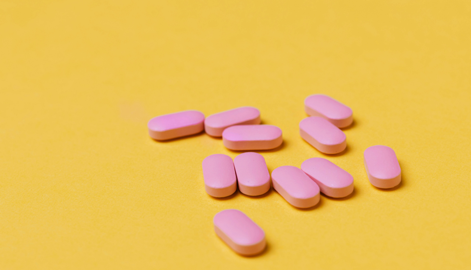 Rozā tabletes uz dzeltena fona